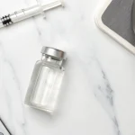 A syringe, vial, and calculator used to plan the total cost of botox.